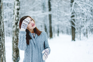 Beautiful young woman adjusting her hairstyle in the winter forest