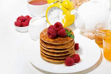 stack of pancakes with fresh raspberries for breakfast on white table