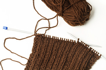 Tejido de lana marr&oacute;n con agujas  sobre fondo blanco aislado. Vista superior