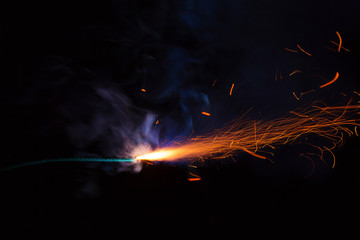Burning fuse with sparks and blue smoke on black background