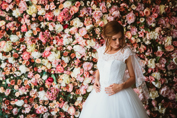 beautiful bride on the background of a wall of flowers