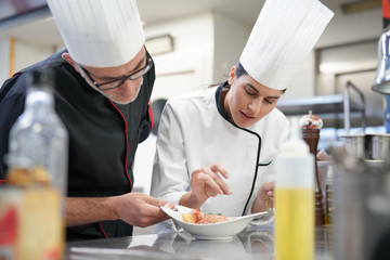 Professional cook chefs in kitchen improving dish composition