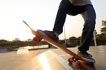 skateboarder legs riding skateboard on skatepark ramp