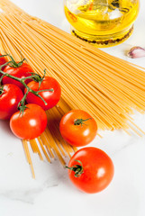 Italian food cooking, ingredients for preparation pasta spaghetti - tomato, garlic, olive oil, spices, white marble background, copy space