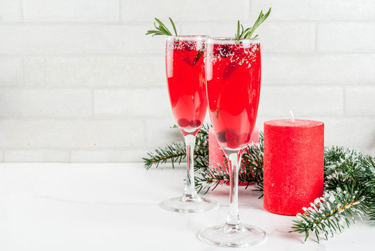 Christmas morning red cranberry mimosa with rosemary, white marble background copy space with christmas decorations