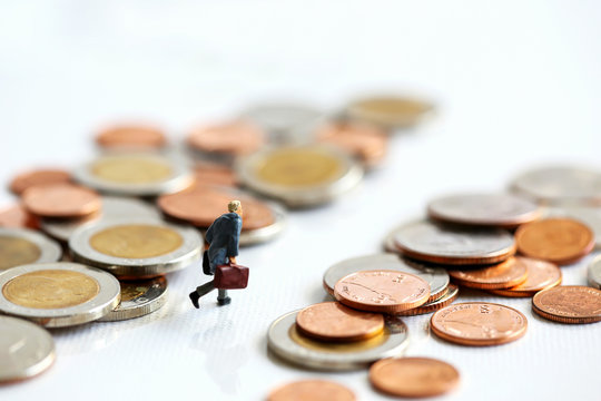 Miniature People : businessman walking between stack of coins