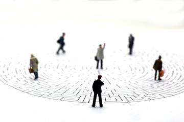 Miniature people: Businessman teams standing on center of maze