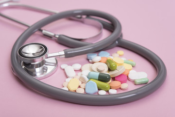 Stethoscope and colorful medicine. Pharmacy on pink background.