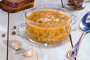 Soup with meat and rice on the plate on wooden table