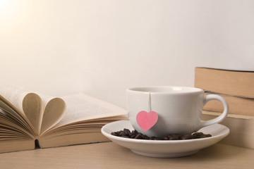 tea cup with red heart on book shelf. Valentines day vintage background.