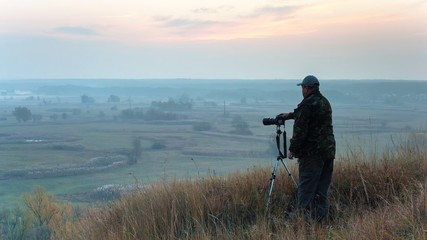the photographer is shooting the autumn landscape with the sunrise by the river