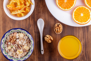 Healthy breakfast. Ceramic bowl with oat flakes, dried fruits, nuts on wood background