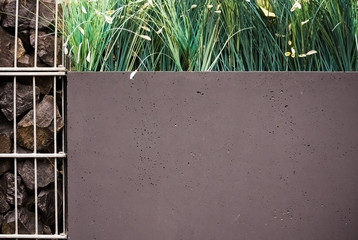 Modern design concrete wall with grass and stones. Space for your text.