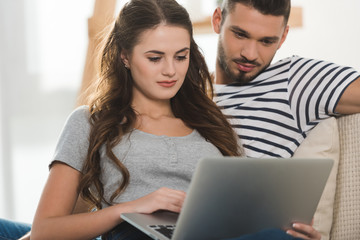 beautiful young couple using laptop together at home