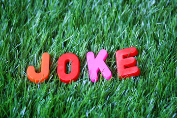 Joke - Colored Plastic Letters On Green Grass Carpet