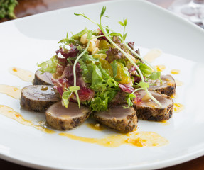 Crusted seared tuna served with vegetables and orange sauce