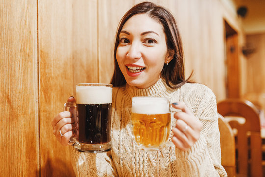 Young asian woman with two big beer mugs at bar in czech tavern