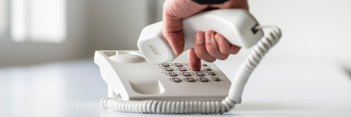 Wide panorama view of a male hand dialing a telephone number - obrazy, fototapety, plakaty