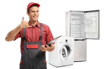 Repairman with a clipboard making a call me gesture in front of a washing machine and a fridge