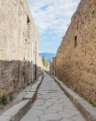 Narrow street with stone blocks floor for carts Pompeii, naples, Italy