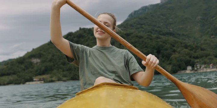 Young woman with long blonde hair canoeing or kayaking. Shot on RED Helium 8K