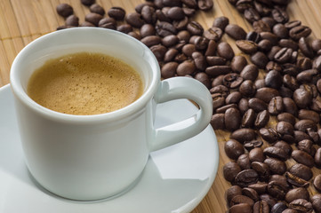 Cup of coffee on the table with scattered grains of black coffee