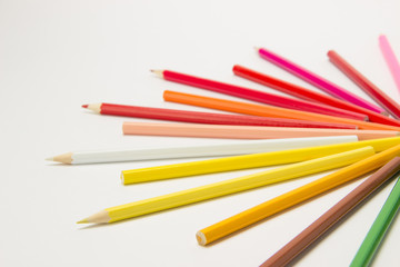 A group of pencils folded in rainbow colors in a circle on a white background