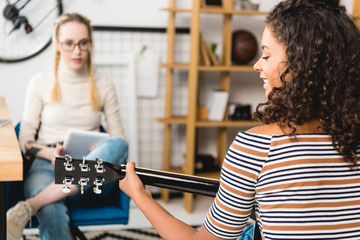 african american girl playing acoustic guitar for friend