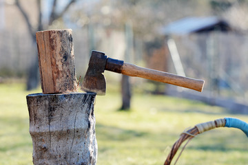 Old vintage axe is stuck in a piece of log wood used for chopping other wood.