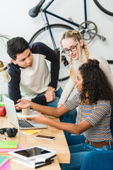 group of multiethnic teens looking at laptop at table