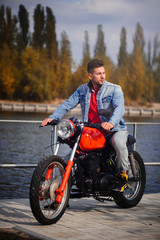 Fototapeta na wymiar young sports fashionable man on a motorcycle, a warm shot, late autumn