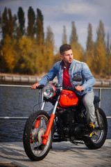 Fototapeta na wymiar young sports fashionable man on a motorcycle, a warm shot, late autumn