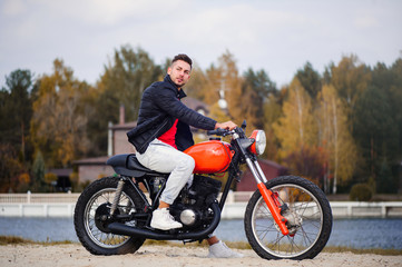 Fototapeta na wymiar large portrait of a young sporty fashionable man on a motorcycle, a warm shot, late autumn