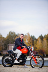 Fototapeta na wymiar young sports fashionable man on a motorcycle, a warm shot, late autumn