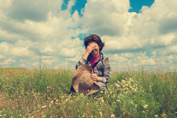 Naklejka na ściany i meble Tired woman sits on the prairie