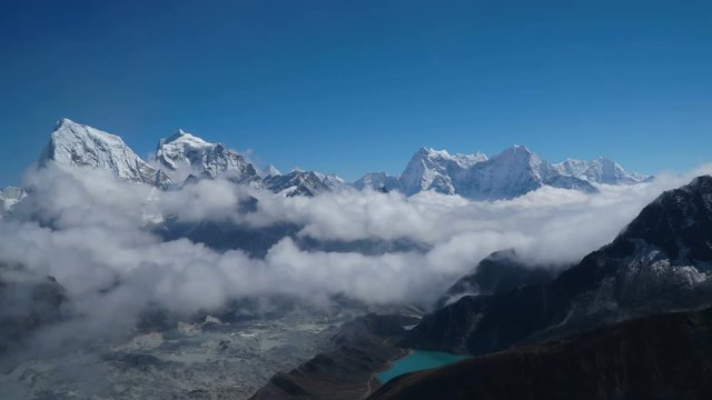 Time lapse. Beautiful clouds over highland Ngojumba Glacier in the Himalayas. View of the snowy peaks and the blue lake. Track to the base camp of Everest. Sagarmatha National Park, Nepal, 4K