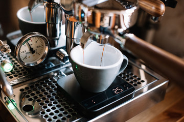 VORONEZH, RUSSIA, 11.17.2017: Delicious fresh morning coffee pouring through the portafilter of Rocket r58V2 espresso machine into a ceramic grey cup, standing on Acaia Lunar black scale