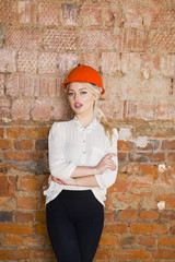 Portrait of architect student or painter with blueprints protect helmet wearing. Brick red background.
