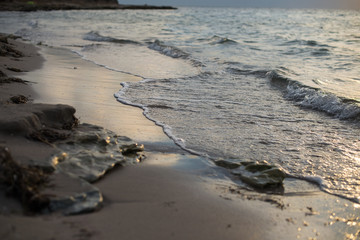 Coast of the sea at sunset. Light waves run to the sandy coast