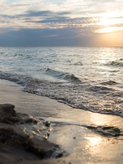 Coast of the sea at sunset. Light waves run to the sandy coast