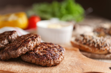 Ingredients for a delicious home burger on a wooden background. roll, bagel, with a juicy cutlet from beef, sauces cheese fresh lettuce leaves