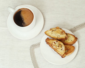 A Cup of coffee and cookies biscotti on the table in a white porcelain ware. Selective focus. Copy space. Top view. Retro toning.