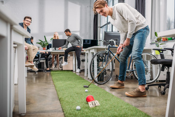 happy people playing in mini golf at modern office - Powered by Adobe