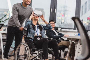 woman in wheelchair using virtual reality glasses at modern office