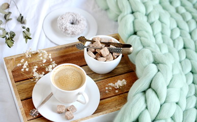 Cup with cappuccino, doughnutt, green pastel giant plaid, bedroom, morning concept