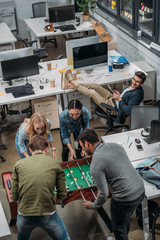 multicultural people playing in table soccer at modern office