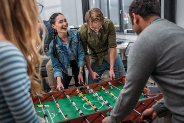 happy multicultural people playing in table soccer at modern office - obrazy, fototapety, plakaty