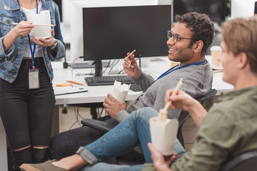 Obraz premium happy multiethnic workers eating thai food at modern office