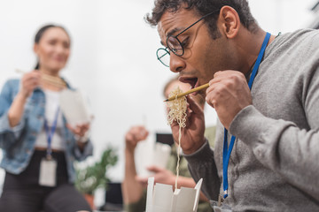african american man eating thai food at modern office