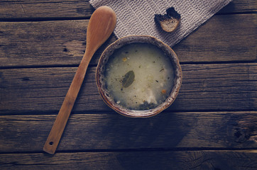 a plate of soup and a spoon on a table of old boards